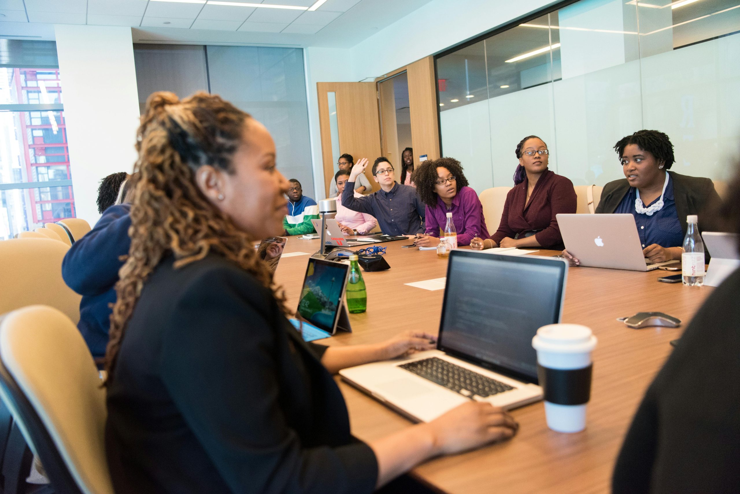 A diverse group of professionals engaging in a team meeting with laptops and discussions in a modern office setting.